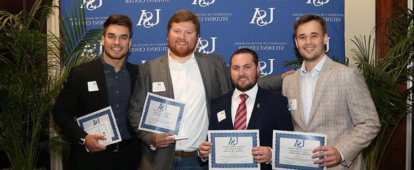 Four male students holding their engineering scholarship certificates.