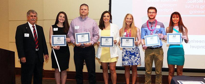 Dr. Steadman with two male and four female students holding their engineering scholarship certificates.